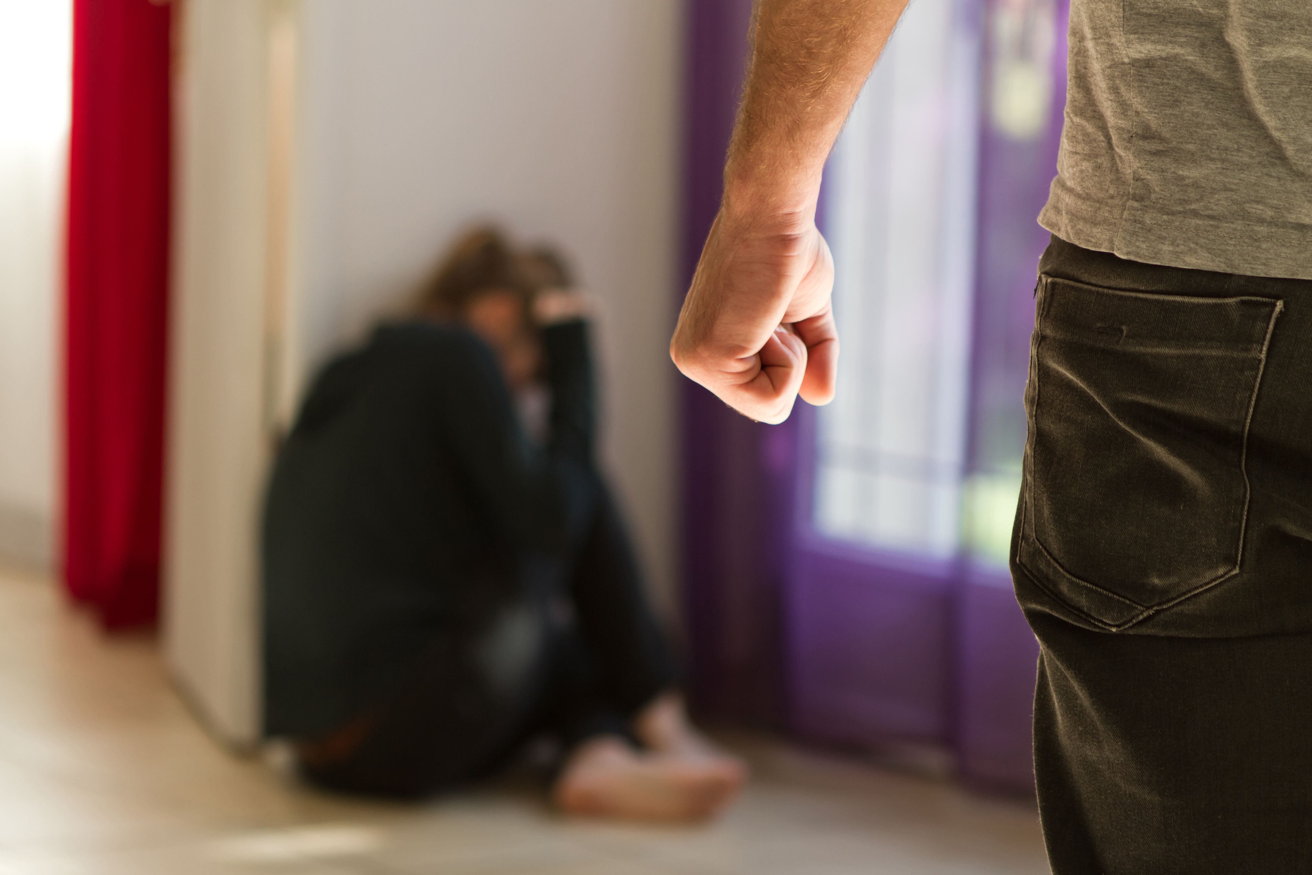 Man with a fist approaching cowering woman - Denton Assault Attorney